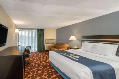 a hotel room with a large bed and a chair at Days Inn By Wyndham Carlisle North in Carlisle