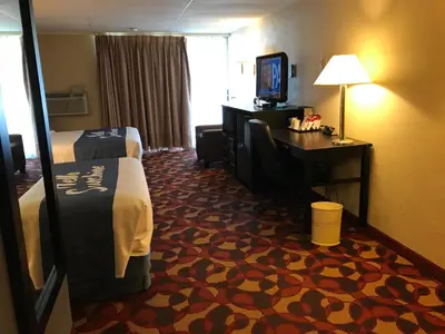 a hotel room with a bed and a desk and a television at Days Inn By Wyndham Carlisle North in Carlisle
