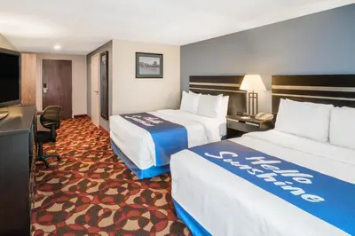 a hotel room with two beds and a desk at Days Inn By Wyndham Carlisle North in Carlisle