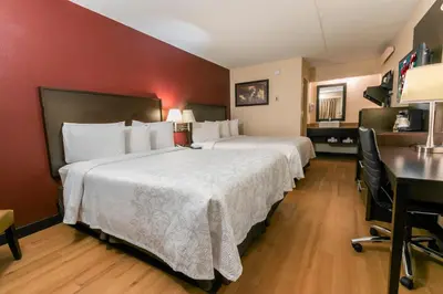 a hotel room with two beds and a desk at Red Roof Inn PLUS+ Wilmington - Newark in Christiana