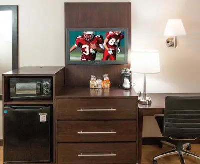 a room with a desk and a television with a football player at Red Roof Inn PLUS+ Wilmington - Newark in Christiana