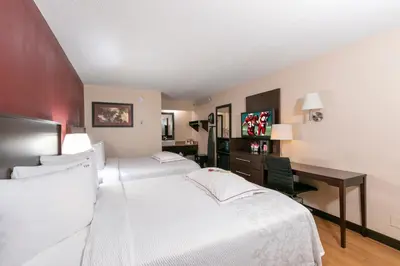 a hotel room with two beds and a desk at Red Roof Inn PLUS+ Wilmington - Newark in Christiana