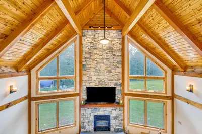 a living room with a stone fireplace and a tv at Spacious and Secluded Forksville Home Fire Pit in Forksville