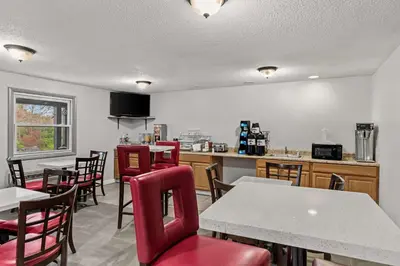 a restaurant with red chairs and tables and a kitchen at Americas Best Value Inn Carlisle in Carlisle