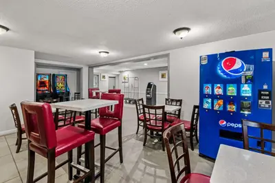 a restaurant with red chairs and a table and a soda machine at Americas Best Value Inn Carlisle in Carlisle