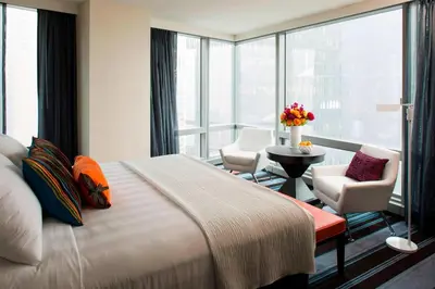 a hotel room with a bed and chairs and a large window at Courtyard by Marriott New York Manhattan/Central Park in New York