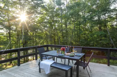 a table and chairs on a deck with the sun shining at Modern Hideaway with Deck and State Forest Access in Livingston Manor