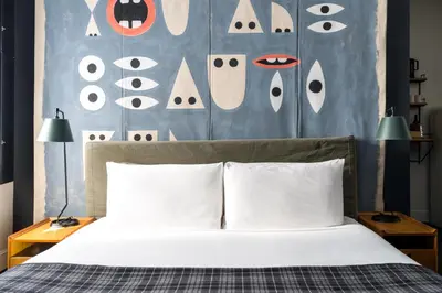 a bedroom with a bed with a headboard with eyes at Ace Hotel New York in New York