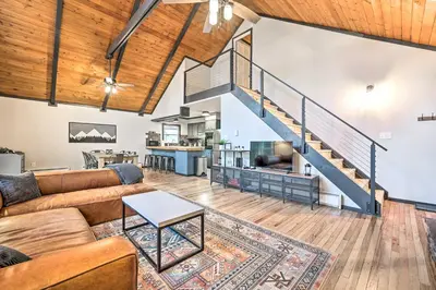 a living room with a couch and a staircase at Game Room, Fire Pit and Deck Spacious Poconos Home! in Lake Harmony