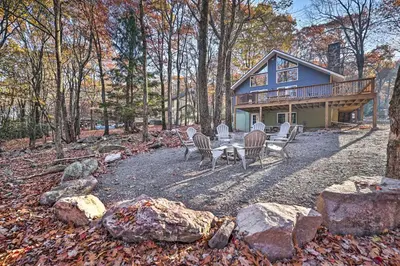 a house with chairs and a table in front of it at Game Room, Fire Pit and Deck Spacious Poconos Home! in Lake Harmony