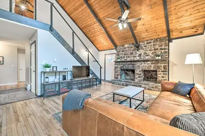 a living room with a couch and a stone fireplace at Game Room, Fire Pit and Deck Spacious Poconos Home! in Lake Harmony