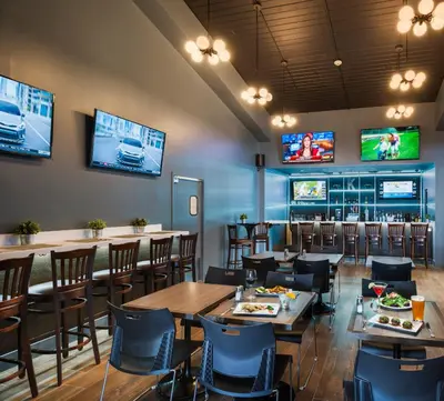a restaurant with tables and chairs and televisions at The Kenilworth Hotel - Airport West in Kenilworth