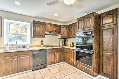 a large kitchen with wooden cabinets and appliances at 20 Mi to Philly Inviting Home with Yard in Wayne! in Wayne