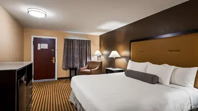 a hotel room with a large bed and a chair at Travelodge by Wyndham Bellmawr in Bellmawr
