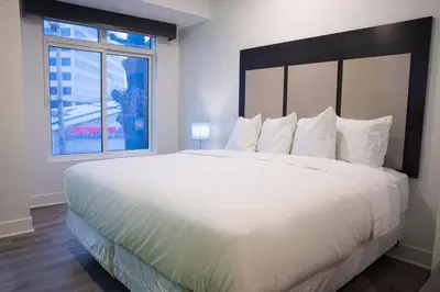 a large white bed in a room with a window at Peachtree Suites - Jersey City in Jersey City
