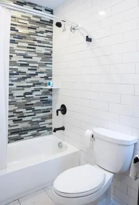 a white bathroom with a toilet and a bath tub at Peachtree Suites - Jersey City in Jersey City