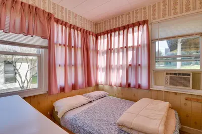 a bedroom with pink curtains and a bed and two windows at Shared Boat Launch Lake Retreat in Ellenville! in Ellenville