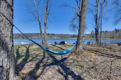 a blue hammock hanging between two trees near a lake at Shared Lake Access and Fire Pit Catskills Getaway! in Ellenville