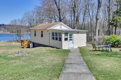 a small white house with a picnic table in a yard at Shared Fire Pit and Kayaks Catskills Lake Retreat! in Ellenville
