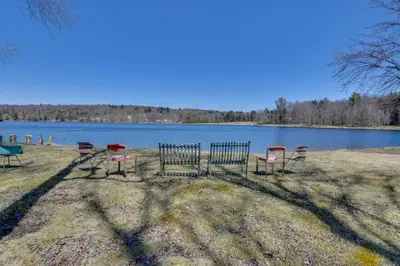 a group of chairs sitting in front of a lake at Shared Fire Pit and Kayaks Catskills Lake Retreat! in Ellenville