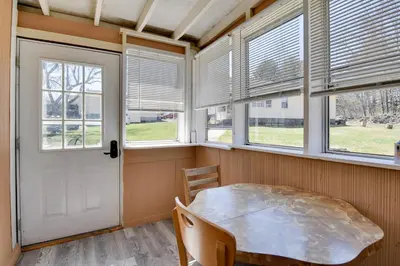 a dining room with windows and a table and chairs at Shared Fire Pit and Kayaks Catskills Lake Retreat! in Ellenville