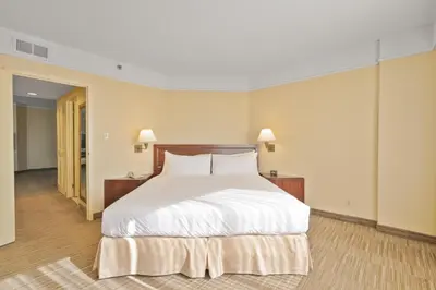 a bedroom with a large bed with white sheets at Harmony Suites Secaucus Meadowlands in Secaucus