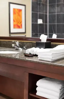 a bathroom with a sink and towels on a counter at Harmony Suites Secaucus Meadowlands in Secaucus