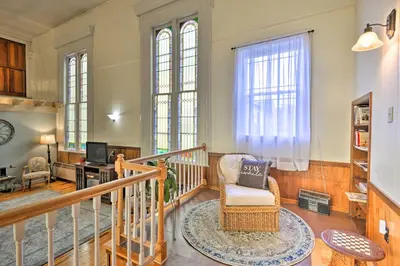 a living room with a staircase and a chair at Lisle Apt Fireplace and Stained Glass Windows! in Lisle