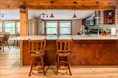 a kitchen with a center island with two bar stools at The Nook Lodge - cabin with hot tub at Shawnee and Camelback Mtn in East Stroudsburg