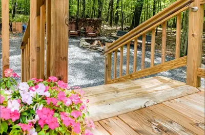 a wooden deck with a bunch of pink flowers at The Nook Lodge - cabin with hot tub at Shawnee and Camelback Mtn in East Stroudsburg