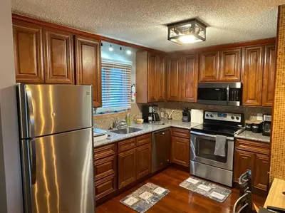 a kitchen with wooden cabinets and a stainless steel refrigerator at Aquatopia Waterpark-Pool-Tennis-Paintball- ZipLine 127 in Tannersville