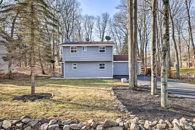 a house in the middle of a yard with trees at Hot Tub, Fire Pit and Game Room Tobyhanna Home! in Tobyhanna