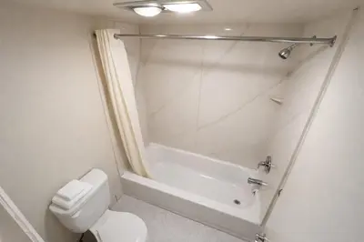 a white bathroom with a shower and a toilet at King's Inn Motel in Reading