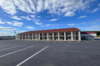 a large building with a red roof in a parking lot at King's Inn Motel in Reading