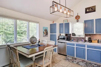 a kitchen with blue cabinets and a table and chairs at Zen Den - Pocono LakeFront with Hot Tub ! in Pocono Summit