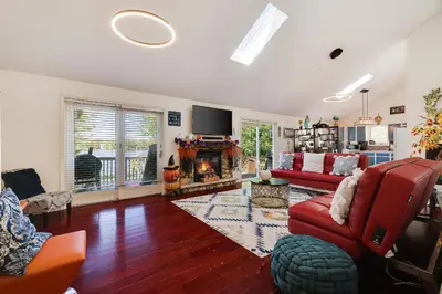 a living room with a red couch and a fireplace at Zen Den - Pocono LakeFront with Hot Tub ! in Pocono Summit