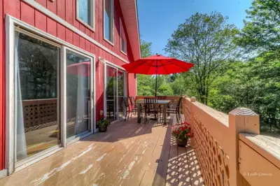 a wooden deck with a table and an umbrella at Beautiful Chalet with Hot Tub & Sauna in Poconos in Long Pond