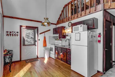 a kitchen with a white refrigerator and wooden floors at Beautiful Chalet with Hot Tub & Sauna in Poconos in Long Pond