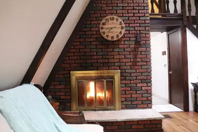 a fireplace with a clock on a brick wall at Escape in our Rain-Forest A-Frame Retreat with Hot Tub at The Kairos Cabin in Harveys Lake