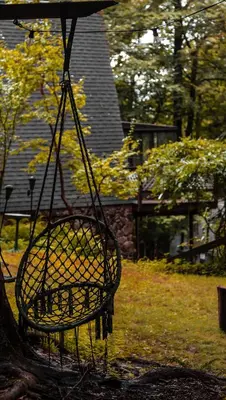 a swing hanging from a tree in a yard at Escape in our Rain-Forest A-Frame Retreat with Hot Tub at The Kairos Cabin in Harveys Lake