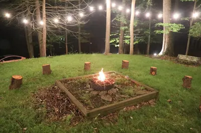 a fire pit in the middle of a field at night at Escape in our Rain-Forest A-Frame Retreat with Hot Tub at The Kairos Cabin in Harveys Lake