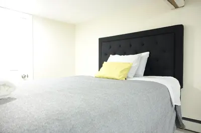 a bed with a black headboard and a yellow pillow at Best EWR Airport Studio-Hot Tub-Free Parking in Hillside