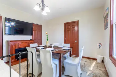 a dining room with a wooden table and white chairs at 1 Bus Stop To NYC-Hot Tub-EWR Airport-Free Parking in Hillside