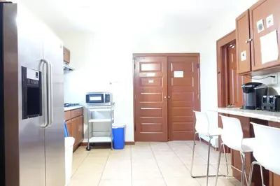a kitchen with a stainless steel refrigerator and white chairs at 1 Bus Stop To NYC-Hot Tub-EWR Airport-Free Parking in Hillside