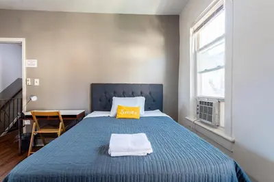 a bedroom with a blue bed with a yellow pillow on it at Best Room To Visit NYC-Subway Access in Newark