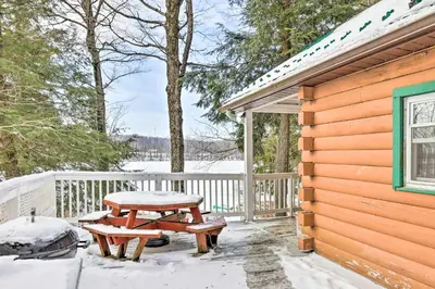 a wooden cabin with a picnic table in the snow at Private Lake Access and Canoes Pennsylvania Cottage in Lakewood