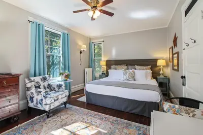 a bedroom with a bed and a chair and a ceiling fan at The South Mountain Inn in Wernersville