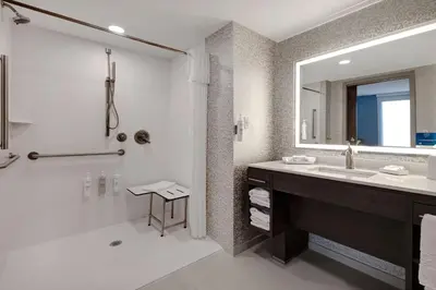 a bathroom with a shower and a sink and a mirror at Home2 Suites By Hilton Wilkes-Barre in Wilkes-Barre