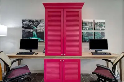 a desk with a red cabinet with two computers on it at Home2 Suites By Hilton Wilkes-Barre in Wilkes-Barre