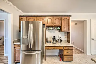 a kitchen with a stainless steel refrigerator and wooden cabinets at East Earl Retreat with Hot Tub Less Than 4 Mi to Town! in East Earl